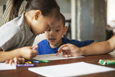 Children looking at mother drawing on paper while sitting in living room - CAVF46710