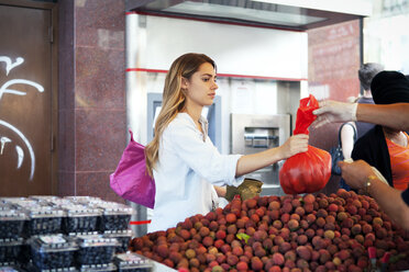 Frau kauft Früchte an einem Marktstand - CAVF46766