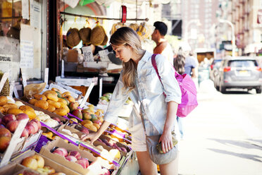 Frau wählt Äpfel an einem Marktstand an der Straße aus - CAVF46767