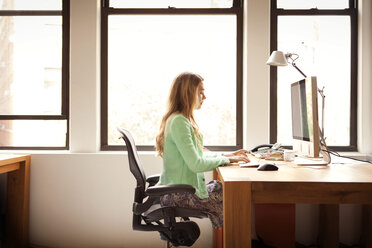 Seitenansicht einer Geschäftsfrau, die einen Computer am Schreibtisch benutzt - CAVF46776