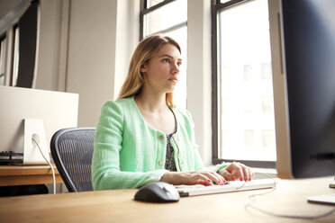 Serious businesswoman working on desktop pc at office desk - CAVF46779