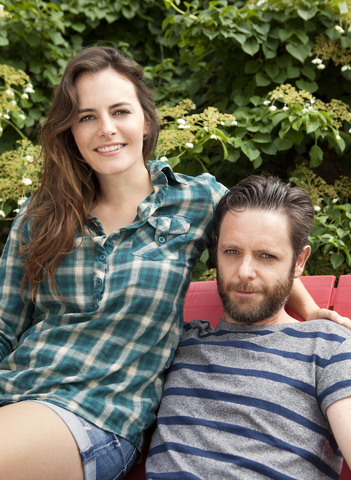 Porträt eines Paares auf einem Stuhl sitzend auf einer Wiese, lizenzfreies Stockfoto