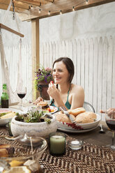 Woman eating food while sitting at table in yard - CAVF46861