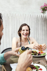Glückliche Frau mit Freund beim Essen am Tisch im Garten sitzend - CAVF46863