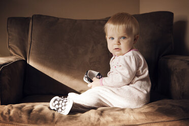 Porträt eines kleinen Mädchens, das zu Hause auf einem Sessel sitzt - CAVF46905