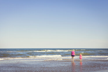 Rückansicht von Großmutter und Enkelin im Meer stehend gegen klaren Himmel - CAVF46936