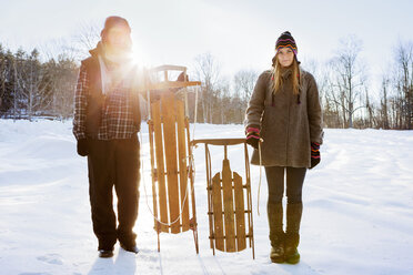Porträt eines Paares mit Schlitten auf einem schneebedeckten Feld - CAVF46943