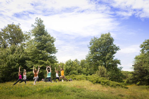 Freunde üben die Krieger 1 Übung auf dem Feld, lizenzfreies Stockfoto