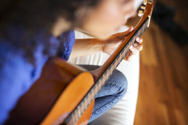 Hohe Winkel Ansicht Frau spielt Gitarre beim Sitzen auf Sofa - CAVF47012