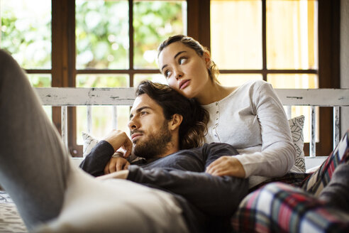 Thoughtful couple leaning on alcove window seat at home - CAVF47040