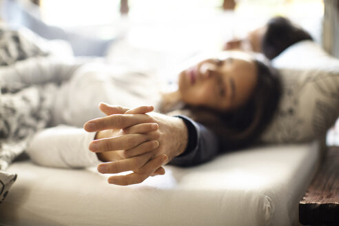 Paar schlafend mit haltenden Händen auf Bett zu Hause - CAVF47055