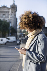 Frau, die ein Mobiltelefon benutzt, während sie auf einer Straße in der Stadt steht - CAVF47077