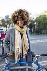 Porträt einer glücklichen Frau mit Fahrrad im Park - CAVF47096