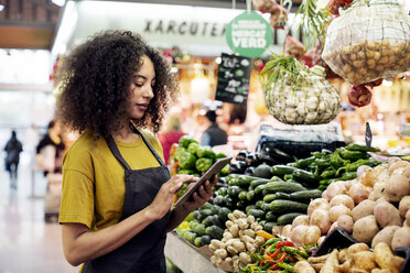 Vendor using tablet computer at market stall - CAVF47122