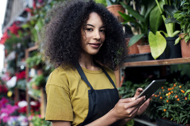 Porträt eines selbstbewussten Besitzers, der an einem Marktstand einen Tablet-Computer benutzt - CAVF47128