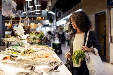 Frau begutachtet Fisch auf dem Markt - CAVF47140