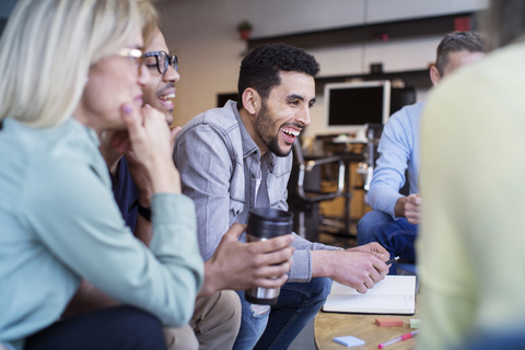 Fröhliche Kollegen diskutieren in einer Besprechung im Büro, lizenzfreies Stockfoto