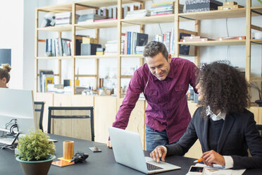 Businesswoman discussing with male colleague at table in office - CAVF47220