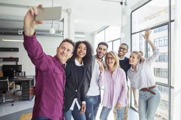 Glückliche Geschäftsleute, die ein Selfie machen, während sie am Fenster im Büro stehen - CAVF47229