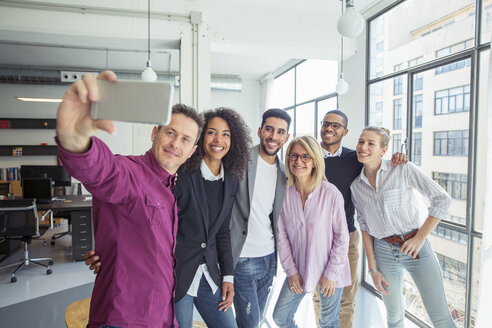 Glückliche Geschäftsleute nehmen Selfie durch Fenster im Büro - CAVF47230