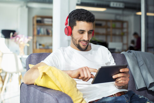 Geschäftsmann mit Tablet-Computer beim Entspannen auf dem Sofa im Büro - CAVF47249