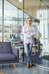 Porträt einer selbstbewussten Geschäftsfrau mit Laptop, die am Fenster im Büro steht - CAVF47252