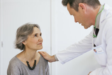 Close-up of doctor comforting senior patient in medical clinic - CAVF47262