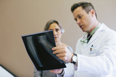 Close-up of doctor and patient looking at x-ray image in medical clinic - CAVF47265