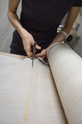 Fashion designer cutting fabric on table in workshop - CAVF47273