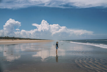 Junge am New Smyrna Beach vor bewölktem Himmel stehend - CAVF47320