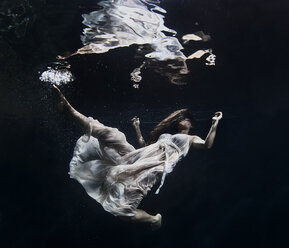 Frau schwimmt bei Nacht im Meer - CAVF47322