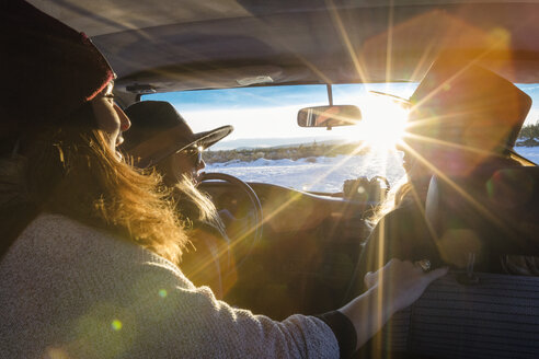 Freundinnen sitzen im Auto an einem sonnigen Tag im Winter - CAVF47323