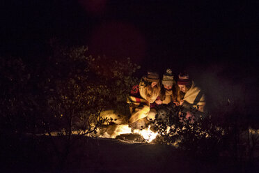 Freundinnen beim nächtlichen Lagerfeuer auf einer Wiese im Winter - CAVF47325