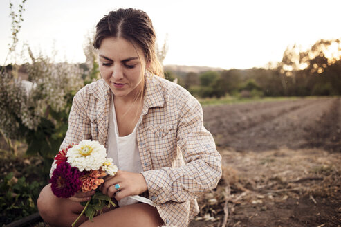 Bäuerin hält schöne Blumen auf einem Feld - CAVF47427