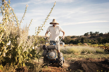Männlicher Landwirt beim Einsatz von Maschinen auf einem Bauernhof gegen den Himmel - CAVF47435