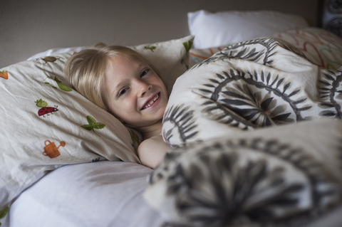 Porträt eines glücklichen Jungen, der im Bett liegt, lizenzfreies Stockfoto