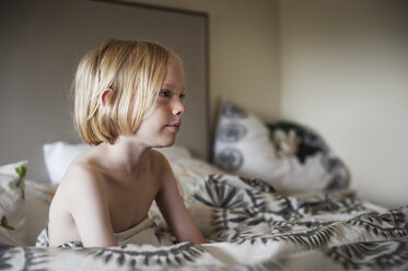 Thoughtful shirtless boy sitting on bed at home - CAVF47459