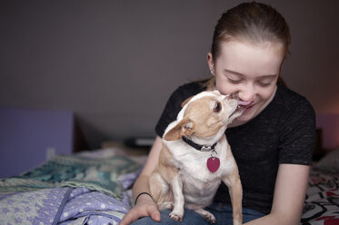 Dog licking happy girl at home - CAVF47485