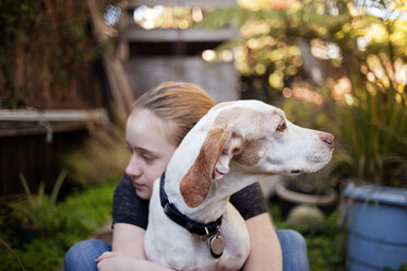 Mädchen umarmt Hund im Hinterhof - CAVF47488