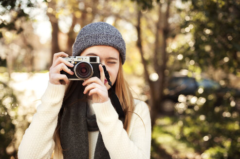 Mädchen fotografiert mit Kamera gegen Bäume - CAVF47502