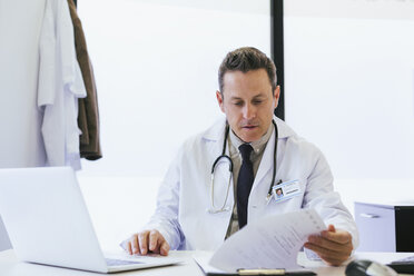 Doctor working while sitting at table in hospital - CAVF47511