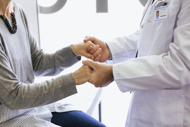 Close-up of doctor holding hands while comforting senior patient - CAVF47515