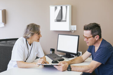 Ärztin im Gespräch mit Patientin im Krankenhaus sitzend - CAVF47518