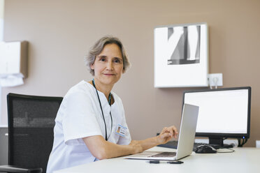 Porträt eines leitenden Arztes bei der Arbeit am Laptop im Krankenhaus - CAVF47520