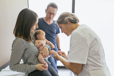 Female doctor examining baby boy with parents at hospital - CAVF47538