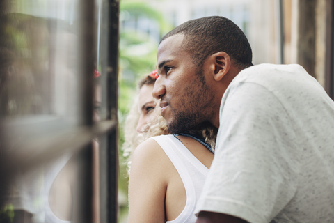 Close-up of thoughtful couple looking through window while standing at home stock photo