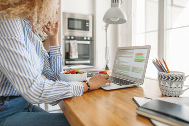 Side view midsection of woman blogging through laptop computer at home office - CAVF47590