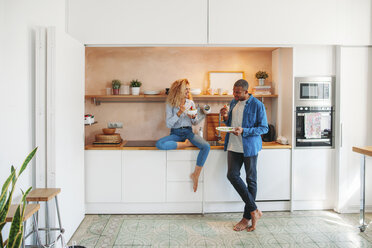 Full length of happy multi-ethnic couple eating salad and sandwich in kitchen - CAVF47594