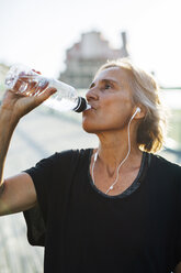 Woman drinking water while listening music - CAVF47631