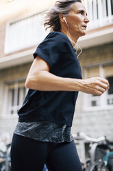 Niedriger Blickwinkel auf eine joggende Frau, die Musik hört - CAVF47634